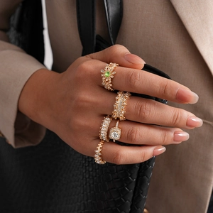 Detailed view of five-piece gold ring set featuring square diamonds and green gemstones