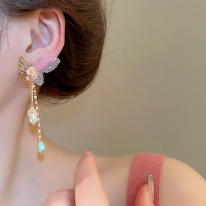 Detail of butterfly tassel earrings with pearls, pink crystals, and a green pendant