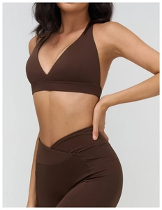 Dettaglio della vita incrociata sui leggings marroni e reggiseno sportivo con scollo a V