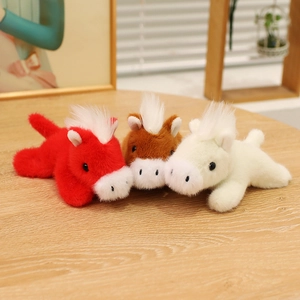 Three cute stuffed plush pony magnets in red, brown and white colors on a table
