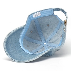 Internal view of light blue denim baseball cap showing 100% cotton label and brass buckle