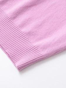 Close-up of pink knit fabric showing soft cashmere texture and ribbed cuff detail