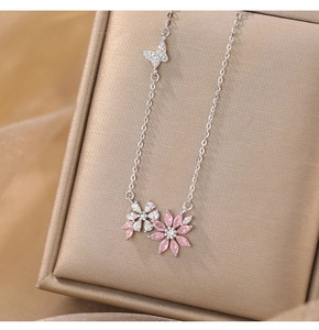 Close-up of pink and white zircon flower pendant with a butterfly detail on silver chain