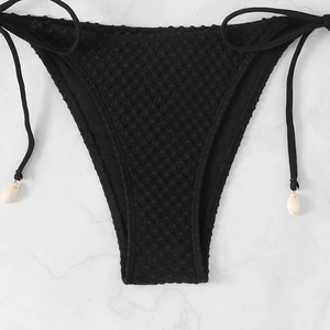 Detail of black bikini bottom with textured jacquard fabric and shell charms