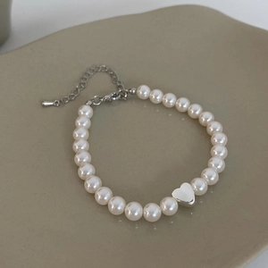Close-up of fresh water pearl bracelet featuring a silver heart pendant and adjustable clasp