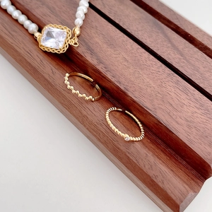 Elegant S925 silver jewelry set with pearl necklace and gold textured rings on wood