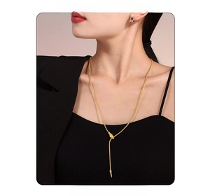 Detail of a gold snake chain necklace featuring a sliding drawstring pendant on model