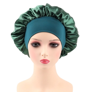 Close-up of dark green satin hair bonnet with wide elastic band on a model head