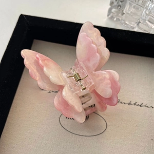 Close-up of pink gradient butterfly hair claw clip with golden glitter details