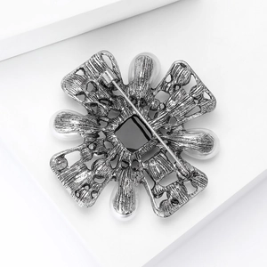 Macro shot of vintage silver brooch back featuring white pearls and black square stone