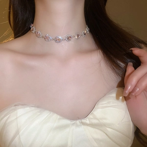 Close-up of a silver necklace with a sparkling pink heart gemstone worn by a model