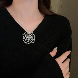 Detailed view of a silver hollow rose brooch with sparkling crystals on a black sweater