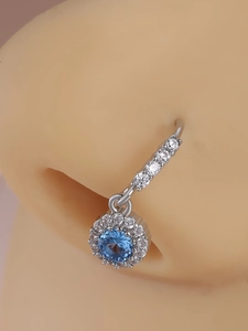 Close-up of silver nose ring featuring a blue gemstone and micro-pave white crystals