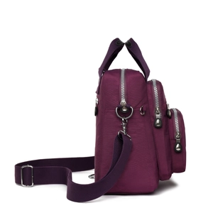 Vue latérale du sac bandoulière en nylon violet avec plusieurs poches zippées et sangle