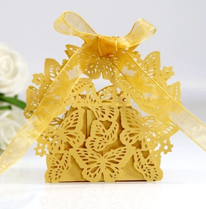 Close-up of golden hollow butterfly candy box with delicate laser cut details and silk ribbon