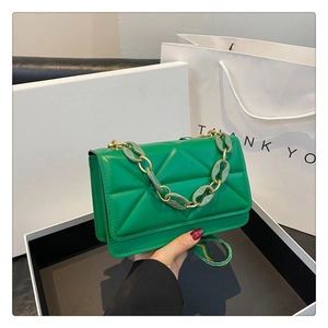 Detail of green quilted crossbody bag with chunky chain strap and gift box display