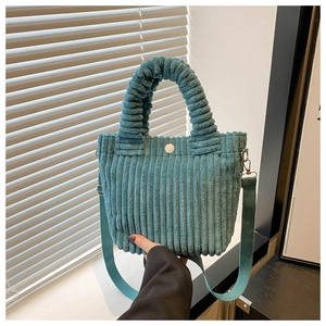 Detail of teal corduroy bucket bag showing pleated handle and white magnetic button closure