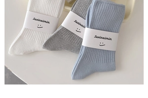 Detail of ribbed cotton socks in white, grey, and blue colors with paper packaging