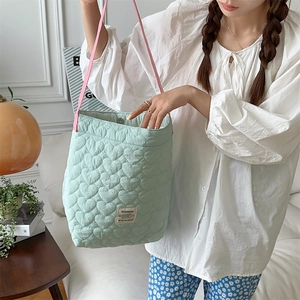 Close-up of heart quilted mint green tote bag with pink handles and magnetic snap