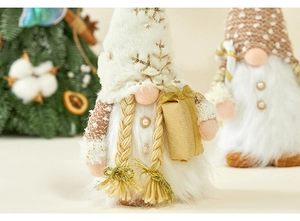 Close-up of white plush Christmas gnomes with golden gifts and festive tree decorations