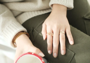 Close-up of gold opening ring with crystal wings and simple band on model hand