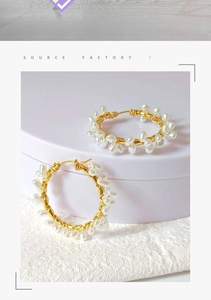 Detailed shot of handmade gold hoop earrings with white baroque pearls on a soft display