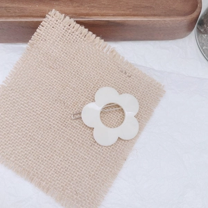 Close-up of white flower hair clip made of acrylic resin on a natural linen background