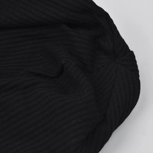 Detailed macro view of the premium black ribbed knit texture on a slouchy beanie hat.