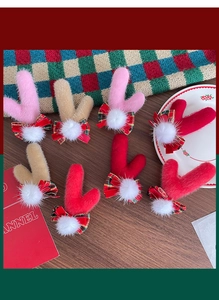 Vue détaillée des pinces à cheveux de renne de Noël avec nœuds à carreaux et pompons