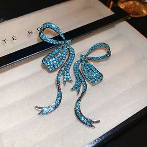 Detailed macro shot of luxury sky blue rhinestone bow tassel earrings in a jewelry box