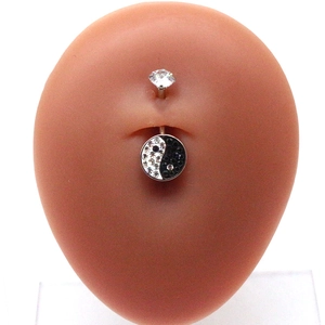 Detailed view of silver navel ring with Yin Yang pendant on professional abdomen model