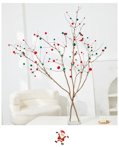 Christmas decorative branches with red, green, and white pom poms in a glass vase