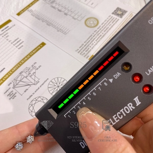 Diamond tester probe checking D color moissanite earrings with GRA certificate shown