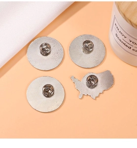 Detailed back view of four silver metal badges with butterfly clutches and grid textures