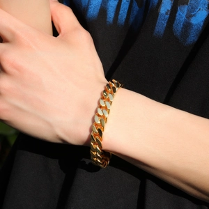 Mens gold Cuban link chain bracelet with spring clasp on wrist, stylish hip hop jewelry
