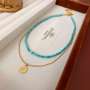 Détail du collier double rang en turquoise avec pendentif tournesol doré sur plateau