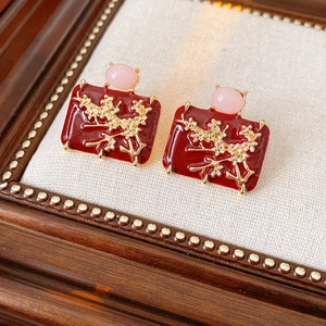 Detail of vintage red enamel earrings with golden floral branch and pink bead decoration