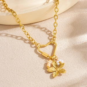 Collier cœur doré avec perles et fleur de muguet sur un fond texturé beige élégant