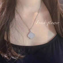 Detailed close-up of a sparkling clover pendant necklace worn by a fashion model