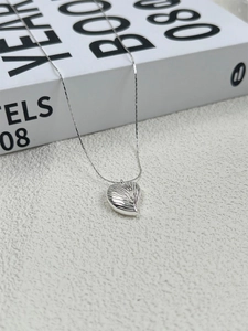 Detailed macro view of 925 sterling silver heart shell pendant on a fine snake bone chain