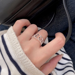 Detailed view of a silver geometric hollow chain ring worn on a finger