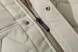 Detail view of quilted puffer jacket with fashion zipper and metal snap button closure