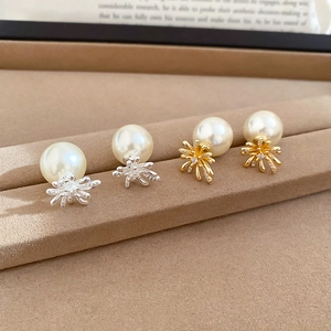 Macro detail of firework pearl earrings in gold and silver finish on soft velvet display