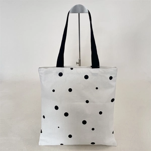 Detailed view of canvas tote bag with black polka dots and black fabric shoulder strap