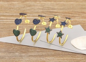 Detail of 18k gold plated C-shaped earrings with colorful zircon stars and hearts