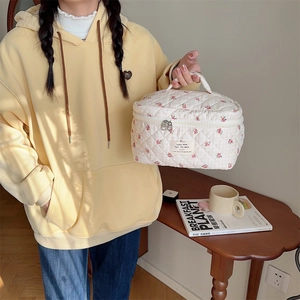 Détail d'une trousse de toilette en coton matelassé à fleurs rouges avec poignée