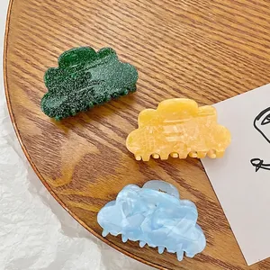 Cloud-shaped acrylic hair claws in emerald green, marbled yellow, and blue finishes