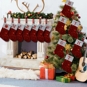 Detail of red sequin Christmas stockings with silver trim and embroidered letters on a fireplace