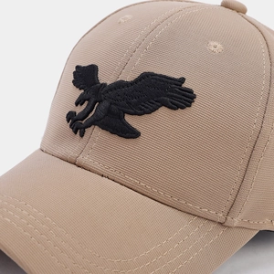 Dettaglio del ricamo dell'aquila nera sul tessuto di cotone beige del cappellino