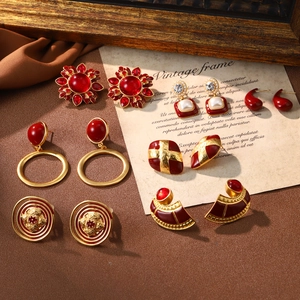 Macro shot of vintage style earrings in gold and red enamel with pearl details